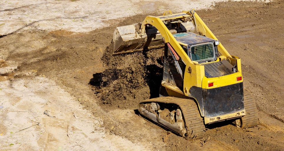 skid steer rental dumping dirt on construction site