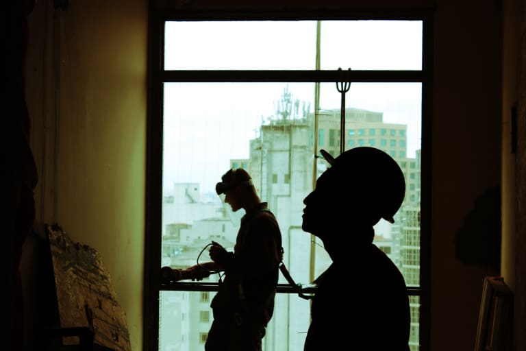 Silhouettes of two construction workers in a building.